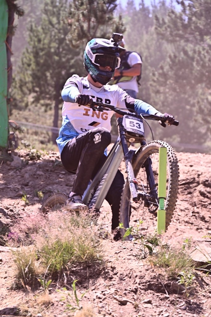 A downhill racer on a dusty World Cup track, Canyon bike, WHOOP number plate 53.